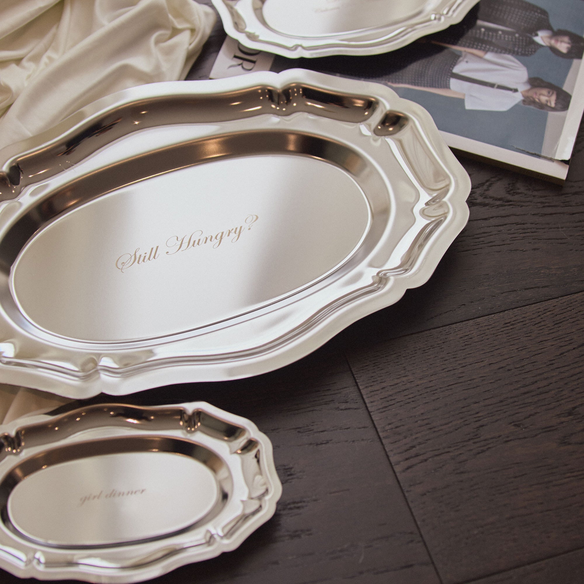 Silver trays with various text engraving on a wooden surface.