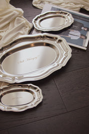 Silver trays with various text engraving on a wooden surface.
